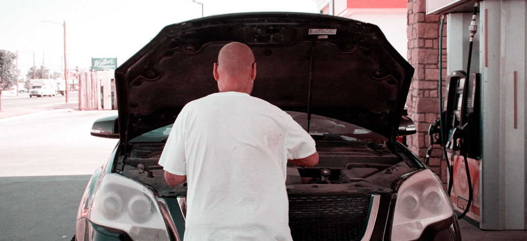 person standing in front of his car with open bonnet 